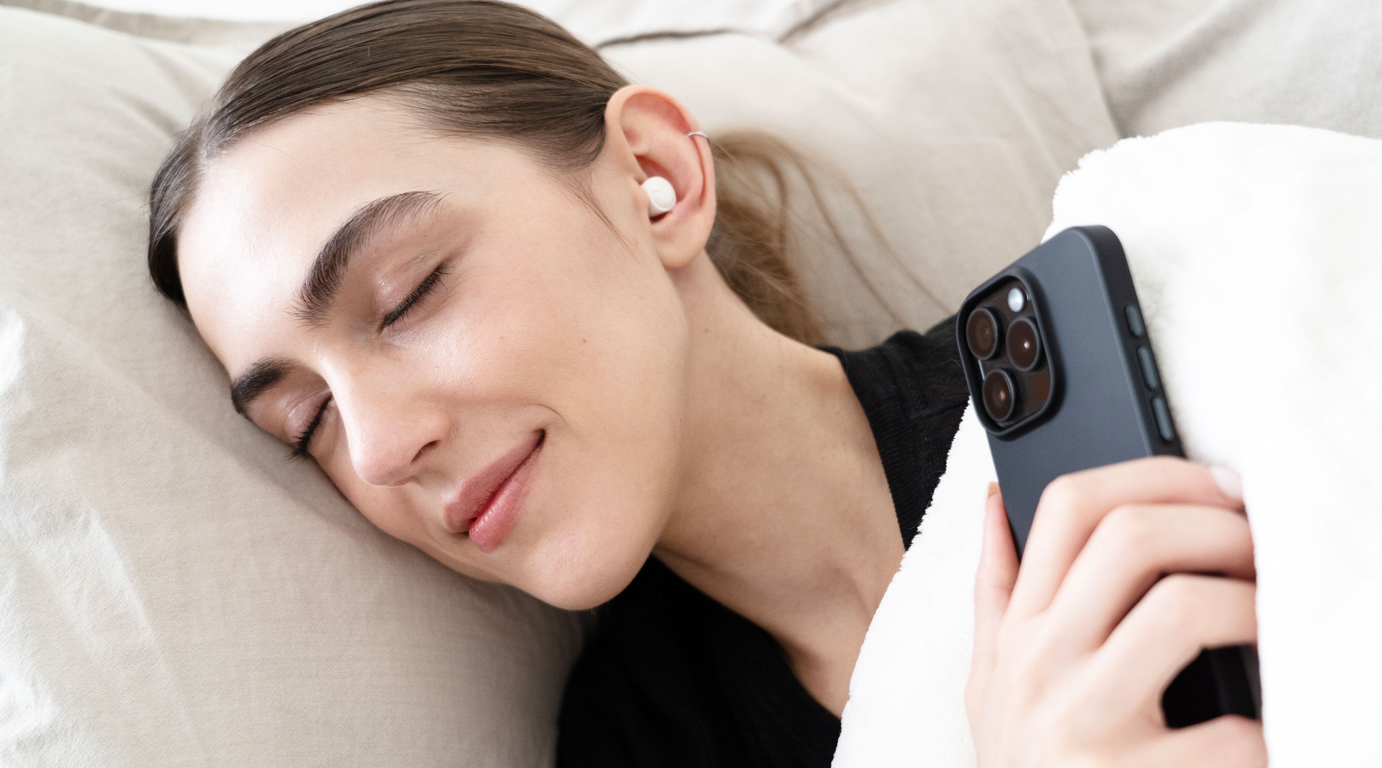 SleepTones wireless sleeping earbuds resting on bedding